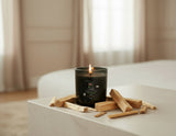 Black candle with wooden wick labeled 'Palma Sante' on a white background
