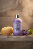 A bottle of  'Peaceful Sleep' lavender body wash, featuring a light purple body with a silver cap and a lavender label, set against a plain white background.